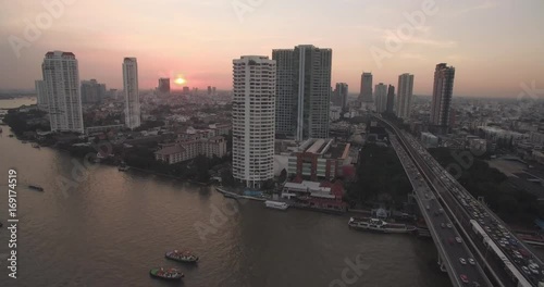 Descending Drone Shot With Sunset Over Chao Phraya River and Saphan Thaksin Bridge, Bangkok, Thailand
 photo