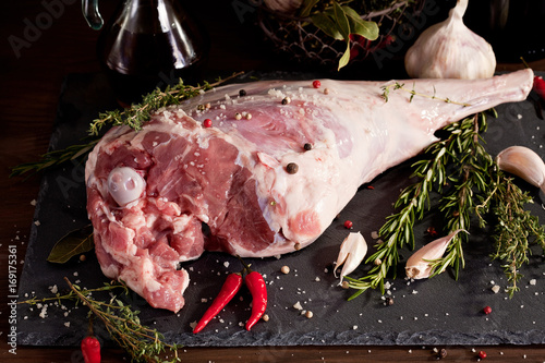 Fresh raw lamb leg ready for roasting with garlic and herbs