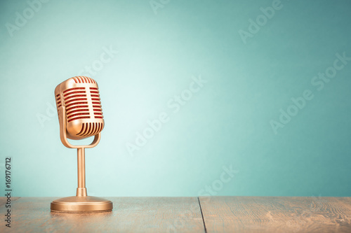 Retro golden microphone for press conference or interview on table front gradient mint green background. Vintage old style filtered photo
