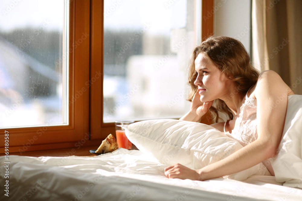 Woman lying in bed at early morning near window. Woman lying in bed at early morning near window.