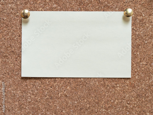 White sheet of paper attached by two buttons to a wooden board