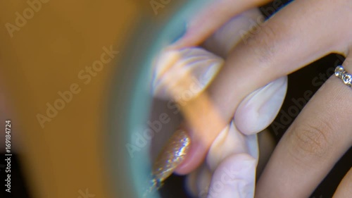 nail master makes gold manicure above lens
