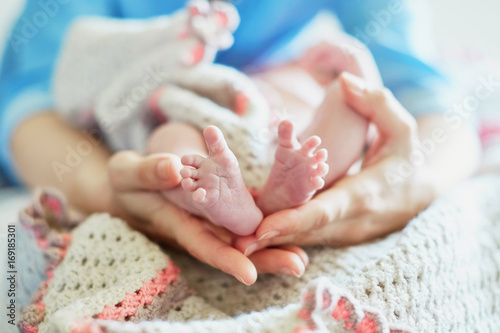 Mother holding newborn baby's feet in her hands