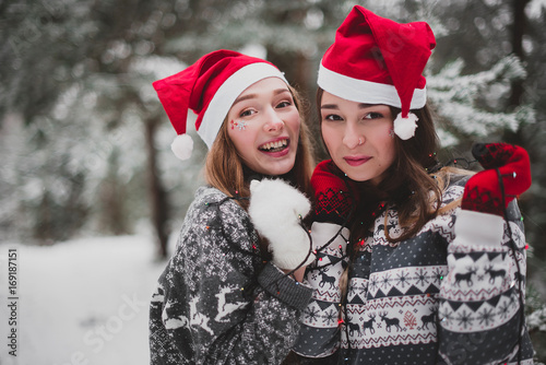 Close up fashion portrait of two sisters hugs and having fun winter time,wearing pink hats, rabbit ears and sweater,best friends couple outdoors, snowy weather