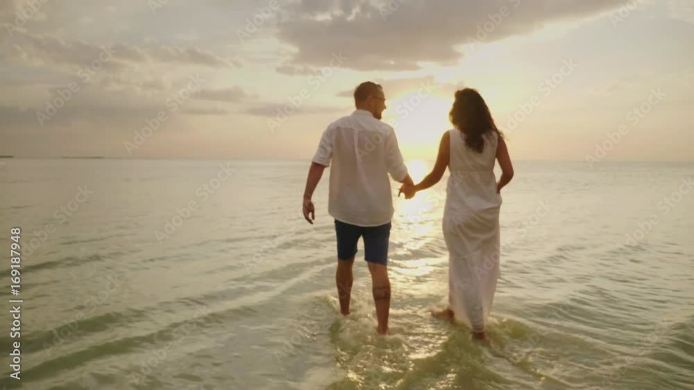 Romantic couple in love walking by the sea at sunset. Honeymoon and vacation by the sea concept Romantic couple in love walking by the sea at sunset. Honeymoon and vacation by the sea concept