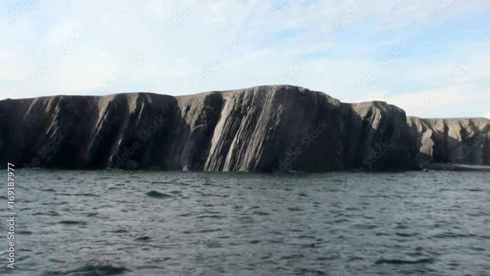 Stone rocks among water surface of Arctic Ocean on New Earth Vaigach Island. Beautiful landscape of wild nature. Quiet and calm ecotourism in Russia. Panorama of way to cold wilderness. Stone rocks among water surface of Arctic Ocean on New Earth Vaigach Island. Beautiful landscape of wild nature. Quiet and calm ecotourism in Russia. Panorama of way to cold wilderness.