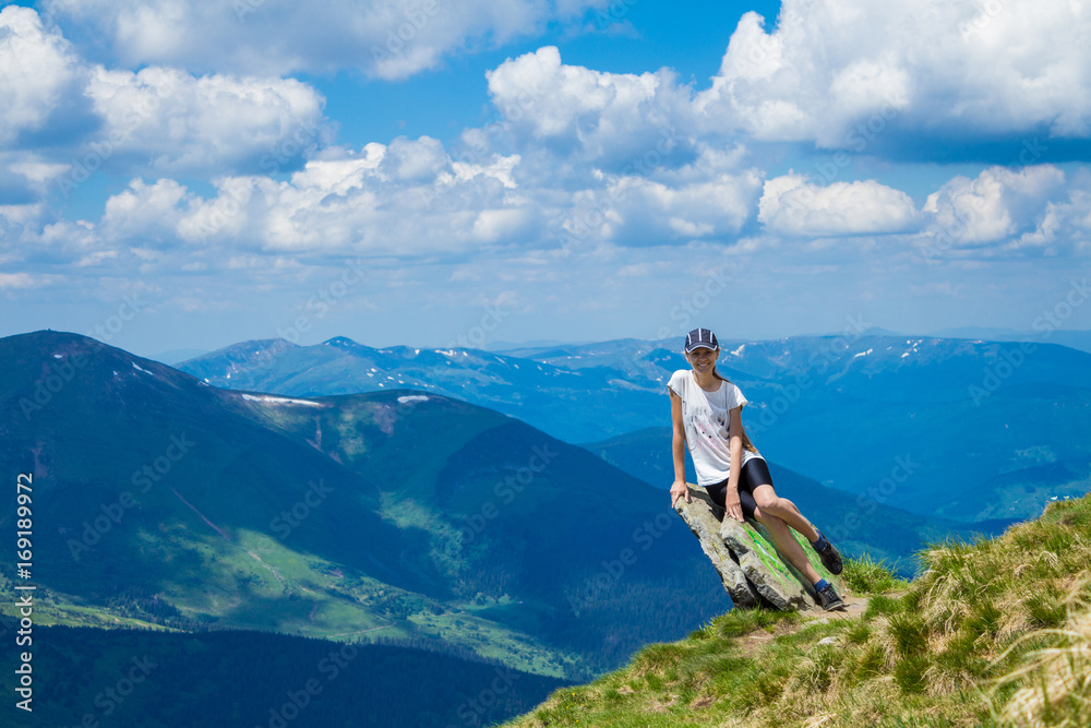 Young woman tourist on cliff`s edge of mountains enjoy the view. Travel and freedom concept