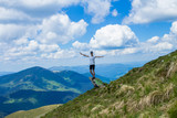 Young woman tourist on cliff`s edge of mountains raise up hand and enjoy beautiful view of sky on top mountain. Travel concept