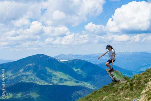 Young woman tourist on cliff`s edge of mountains enjoy the view. Travel and freedom concept