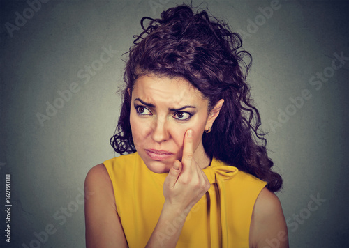 Young woman pulling down eyelid checking her eye looking in morrow feels unwell has black circles