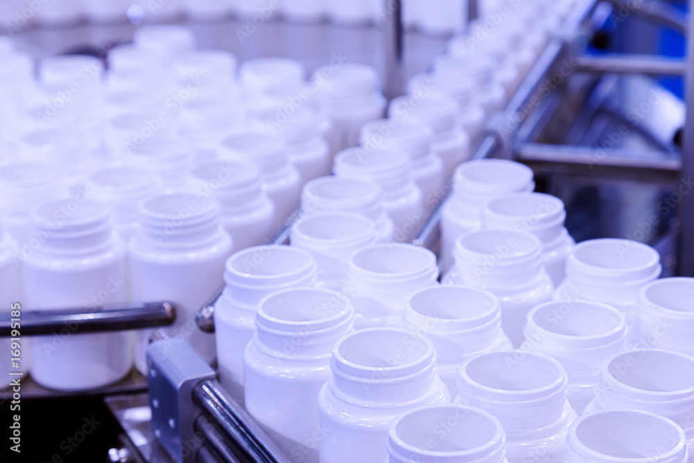 white plastic bottle on the production line of the conveyor at filling machine in the factory. selective focus. white plastic bottle on the production line of the conveyor at filling machine in the factory. selective focus.