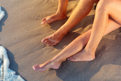 Vacation holidays. Close up of male and females feet on the beach.