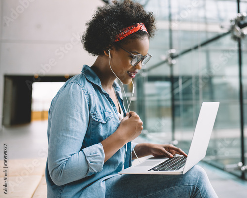 Фотография Young African female student working on a laptop on campus