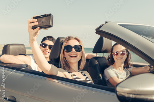 Happy friends taking selfie in car © fotofabrika