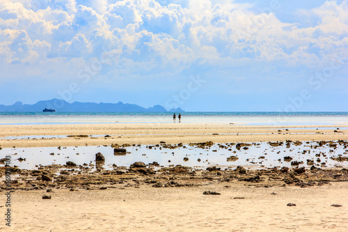 Lovers walk on the beach in a beautiful clouded atmosphere.