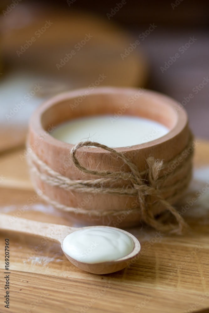 Milk in wooden cup. Spoon with homemade cream. Kitchen in the village Milk in wooden cup. Spoon with homemade cream. Kitchen in the village