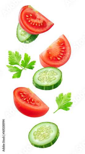 Isolated vegetables. Mixed slices of cucumber and tomato floating in the air isolated on white with clipping path