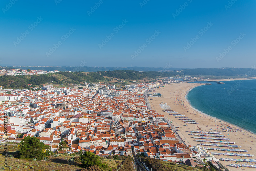   Nazare beach in Portugal in summer, people in holidays and tiles roofs of the village
