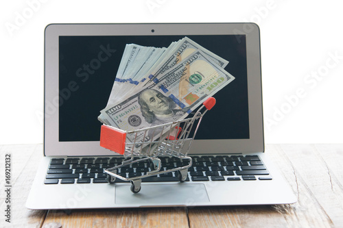 Computer laptop, money, and trolley as for online shipping background.