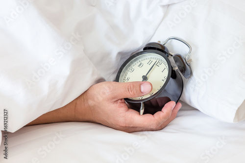 Man extend hand reaching to turn off alarm clock switch