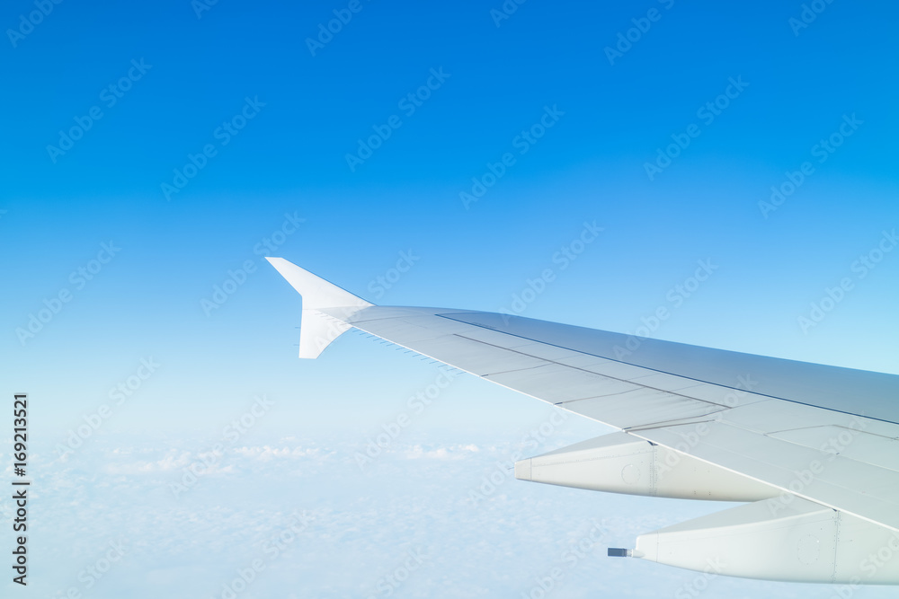 Airplane wing above cloud seen through window Airplane wing above cloud seen through window