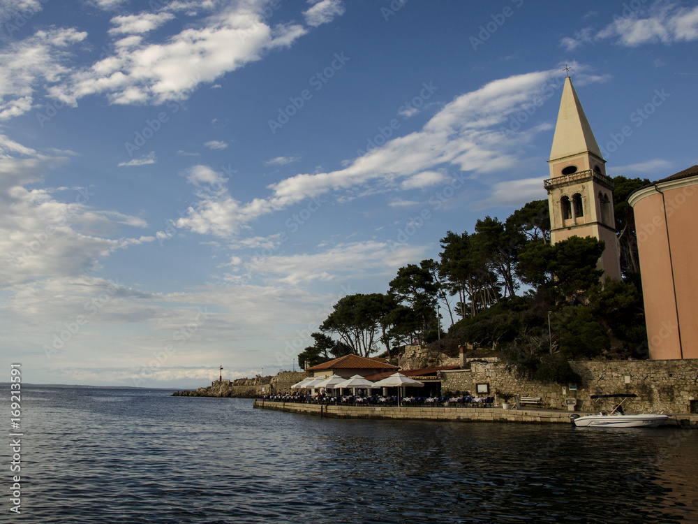 the sea , the clouds and the bell tower, view of a church at the seaside, veli losinj, croatia