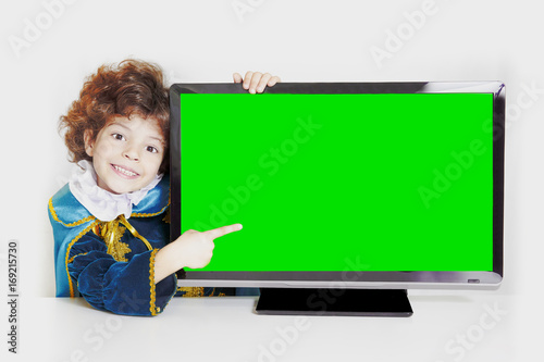 Cute curly red-haired prince points his index finger on a green screen set. Close-up. Gray background.