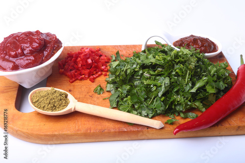 Fresh green cilantro, coriander leaves, tomato paste, chili pepper and spices on a wooden board. Ingredients for meat sauce.