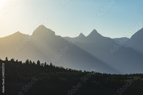sun rays wrapping around giant mountain peaks before sunset
