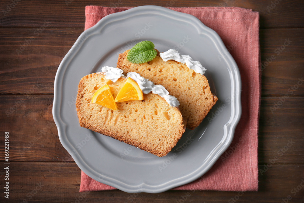 Plate with delicious sliced citrus cake with whipped cream on wooden table Plate with delicious sliced citrus cake with whipped cream on wooden table