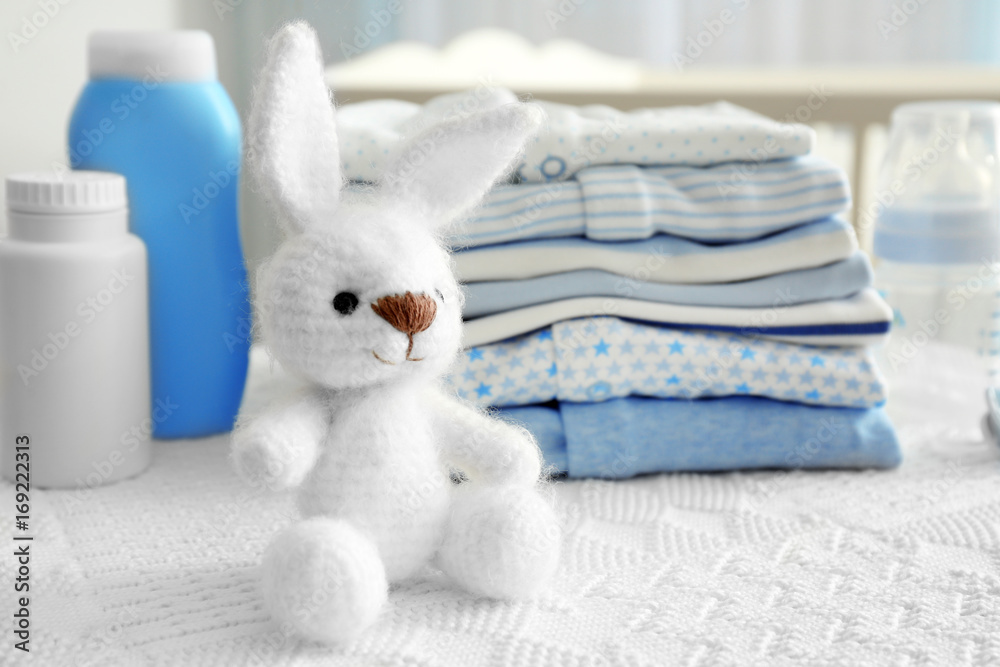 Obraz premium Knitted toy bunny and baby clothes on table