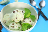 Bowl with delicious mint chocolate chip ice cream on color background, closeup