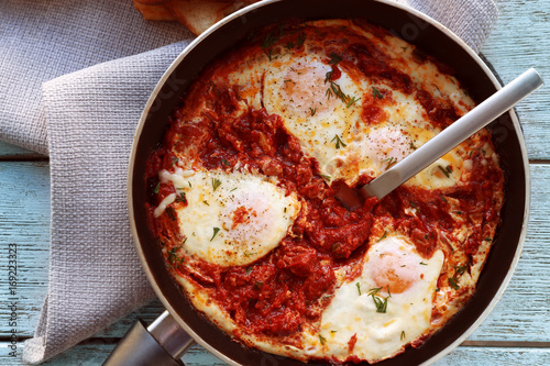 Frying pan with eggs in purgatory on table