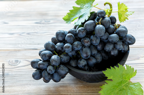 Bunch of black grapes in a wooden bowl.