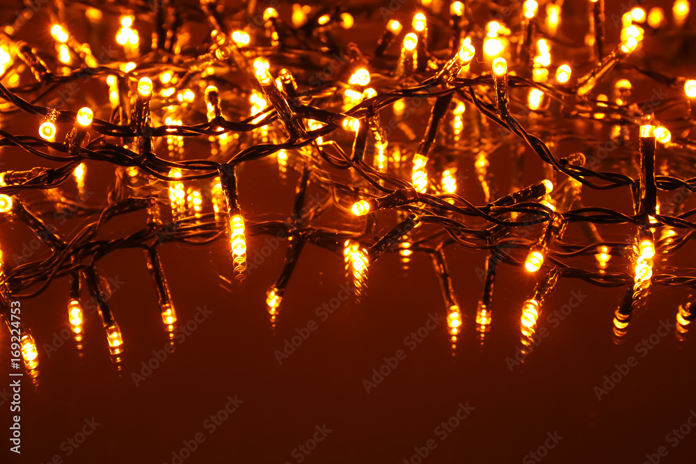 Glowing Christmas lights on color background, close up