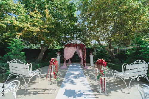 Оформление  арки для свадебной церемонии  красными цветами и розовой тканью