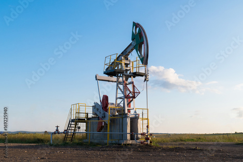 working oil pump on the ground among the green fields