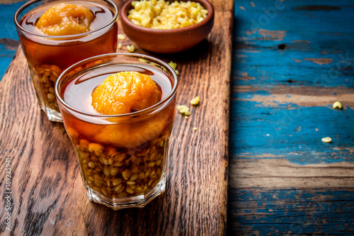 Mote con huesillo. Traditional Chilean drink made from cooked husked wheat and dried peach on wooden board, rustic blue background photo
