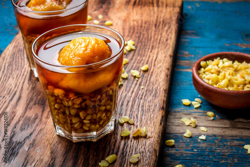 Mote con huesillo. Traditional Chilean drink made from cooked husked wheat and dried peach on wooden board, rustic blue background