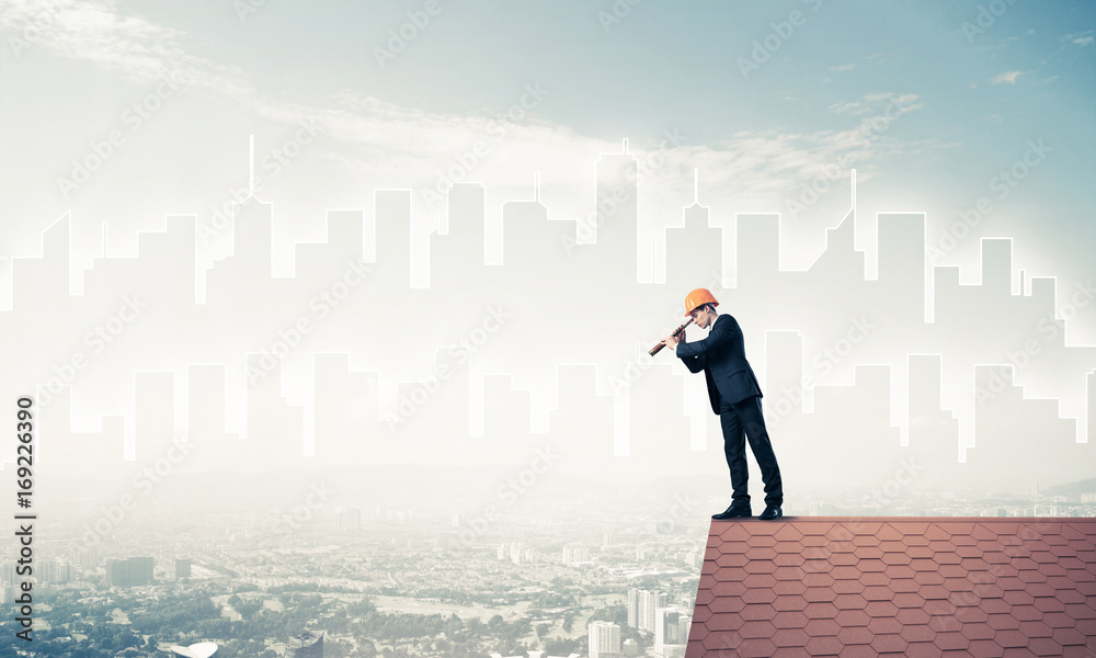 Engineer man standing on roof and looking in spyglass. Mixed med Engineer man standing on roof and looking in spyglass. Mixed med