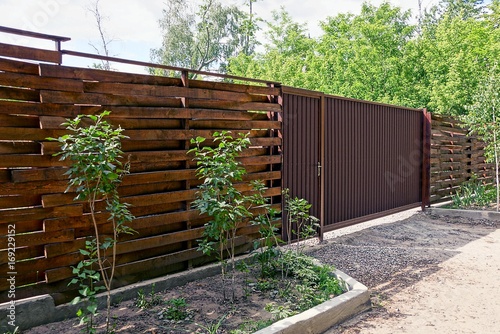 Деревянный коричневый забор и закрытые ворота на улице у дороги