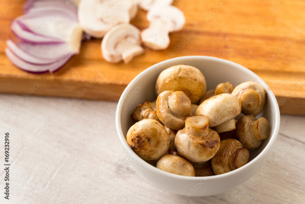 Fried champignon mushrooms in a bowl on the table. Fried champignon mushrooms in a bowl on the table.