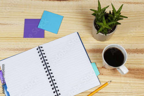 Open note book on a table with a potted cactus