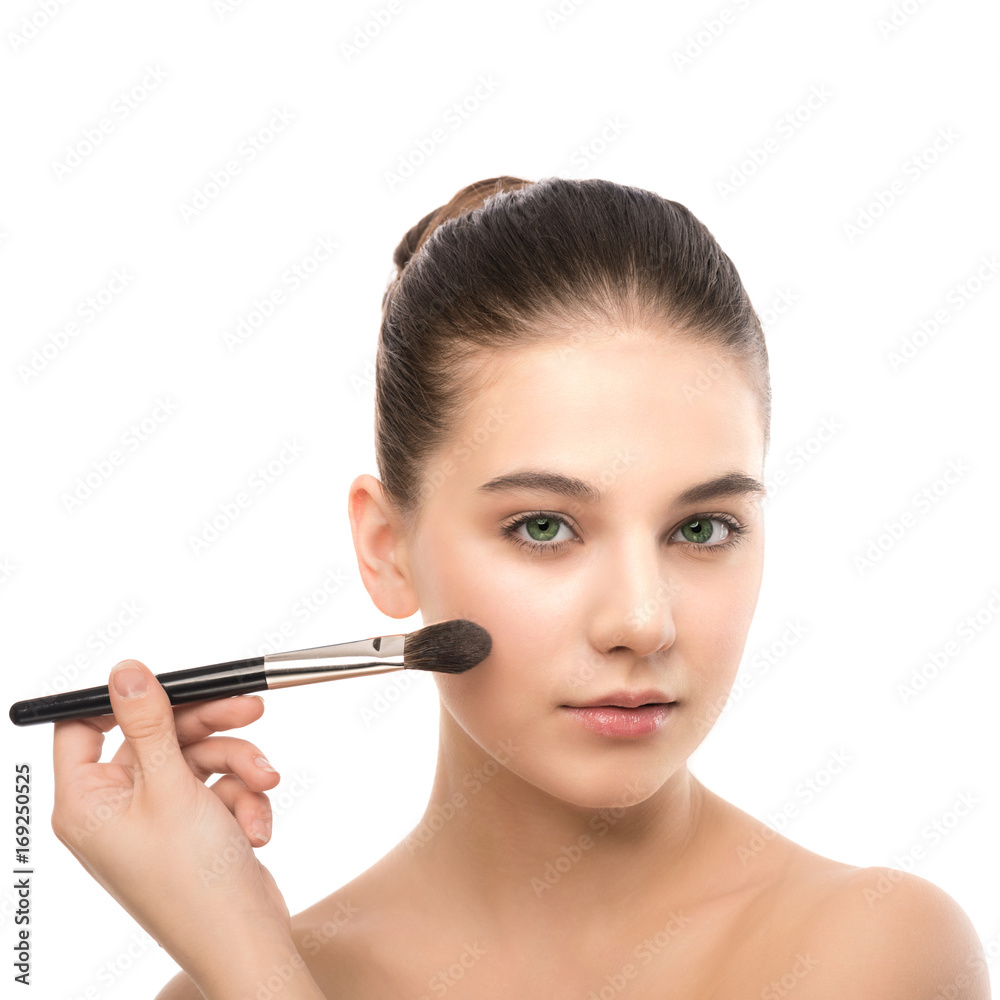 Portrait of beautiful young brunette woman with clean face. Beauty spa model girl with perfect fresh clean skin applying cosmetic brush. Youth and skin care concept. Isolated on a white background.