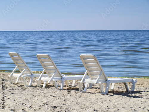 Three sun loungers on a deserted beach