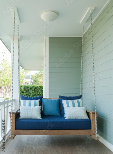 outdoor wooden porch swing bench with blue pillows.