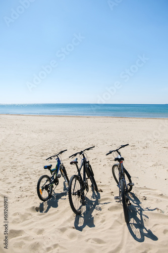 Three bicycles are on the beach on sea background