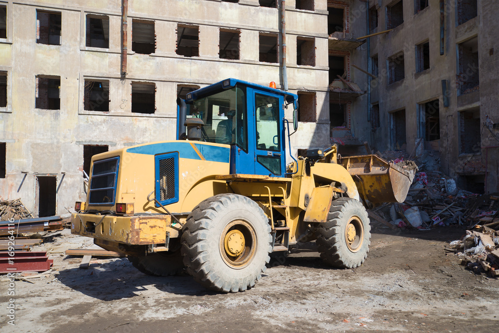 Heavy front loader clears debris on the reconstruction of old residential building Heavy front loader clears debris on the reconstruction of old residential building