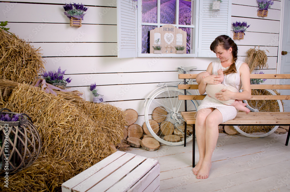 Breastfeeding baby. Young mother holding her newborn child. Mom nursing baby. Woman and new born boy in white bedroom.