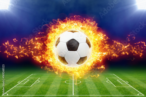 Burning soccer ball above green football stadium © IgorZh